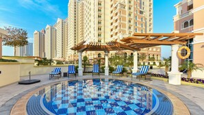 A swimming pool with blue mosaic tiles, surrounded by lounge chairs and a pergola. - VB22 & VB23 by Qatar Coral (Doha)