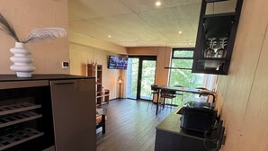 Een moderne keuken met een inbouwkoelkast, een eethoek met tafel en stoelen, en een groot raam dat zorgt voor natuurlijk licht.