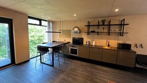 Een moderne keuken met een centraal eiland, een ingebouwde oven en een groot raam met uitzicht op groen.