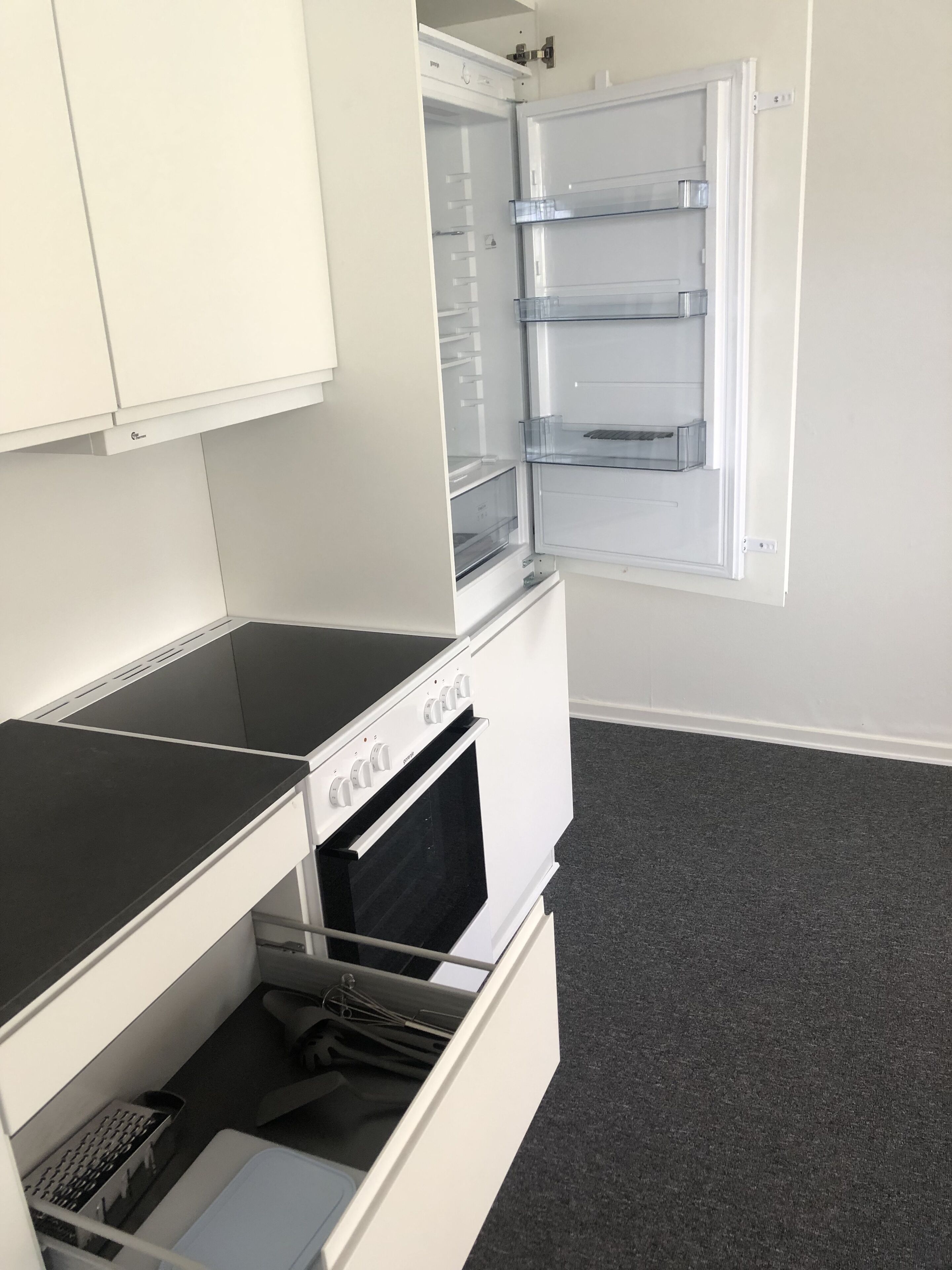 A compact kitchen with a built-in oven, a microwave, and a refrigerator with multiple shelves.