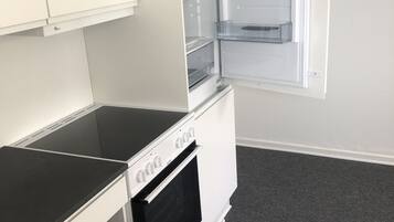 Una cocina compacta con horno integrado, microondas y nevera con varios estantes.