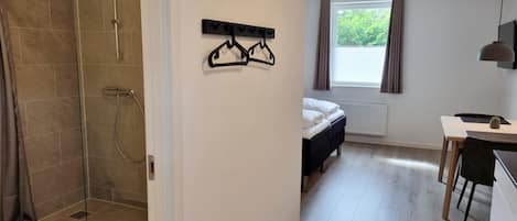 Una habitación de hotel moderna con ducha, cama, escritorio y ventana con cortinas.