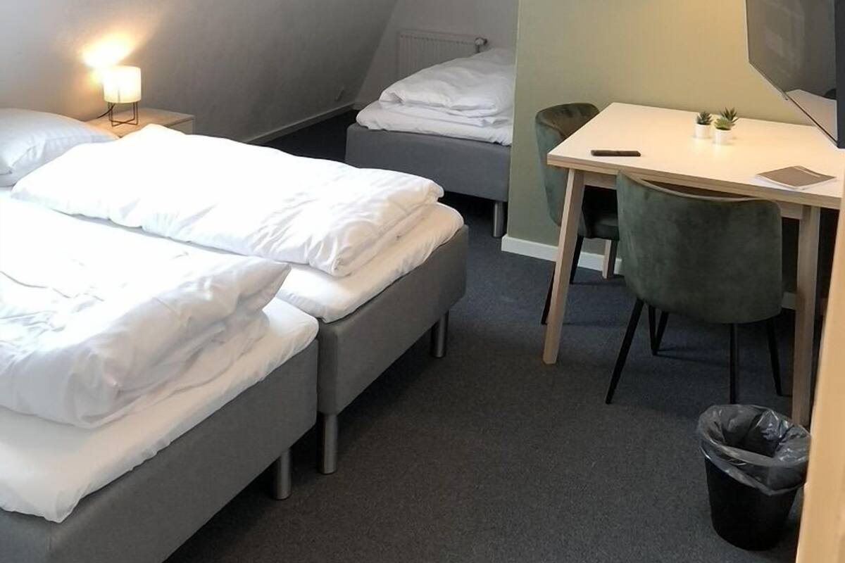 A small, modern bedroom with a sloped ceiling, a bed, a desk, and a chair.