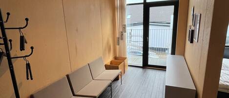 A modern waiting area with a sofa, a small table, and a coat rack.