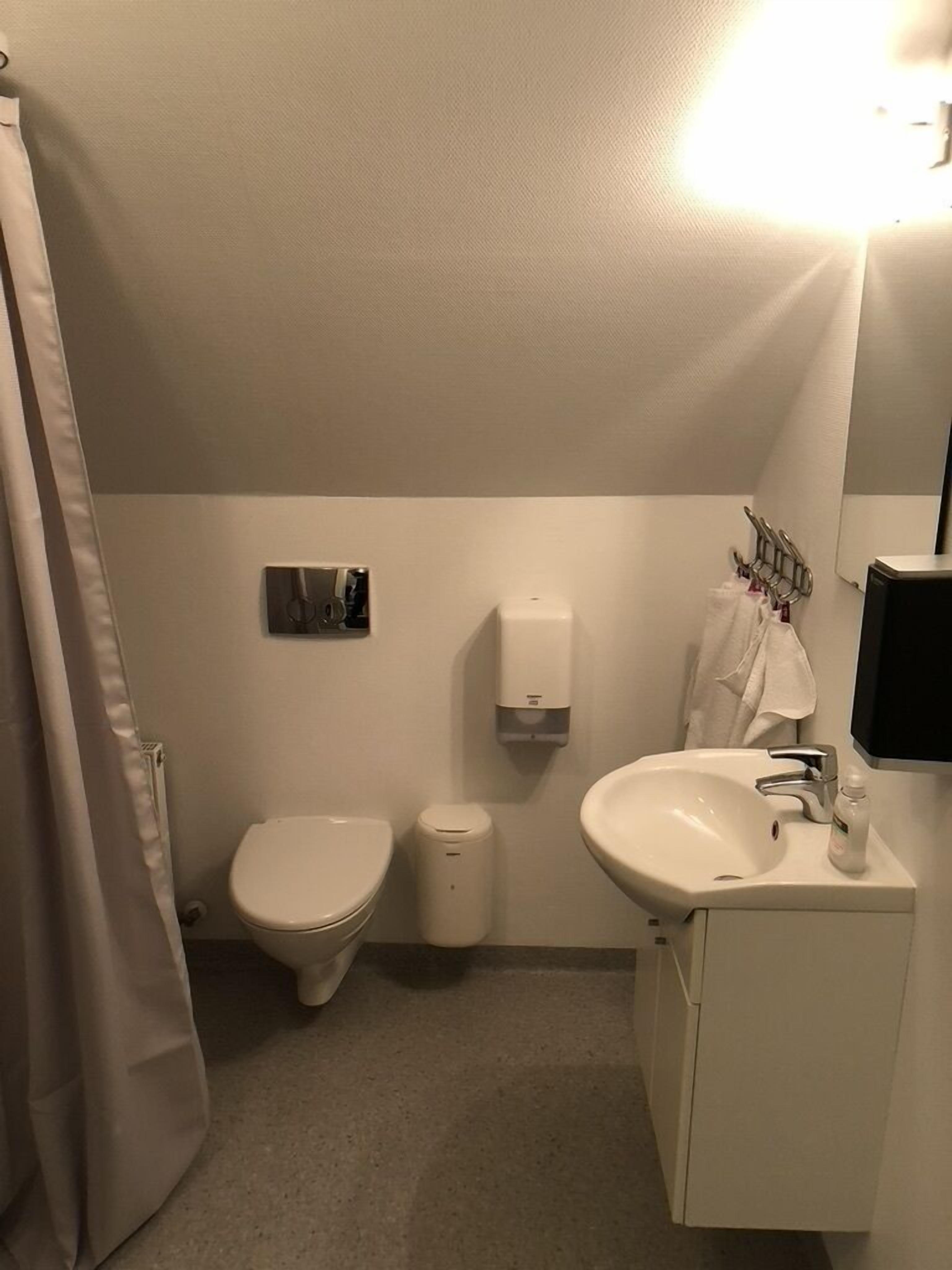 A small, clean bathroom with a toilet, sink, and hand dryer.