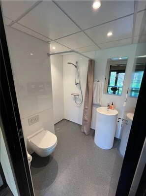 A modern bathroom with a toilet, shower, and sink.