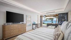 Une chambre avec un grand lit, une télévision, un bureau et une vue sur l’océan.