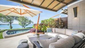Une terrasse extérieure moderne, dotée d’une piscine, d’un espace salon et offrant une vue sur la mer.