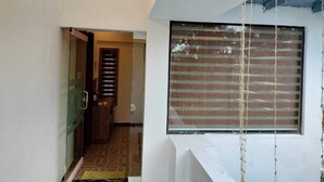 A modern interior with a large window covered by blinds, a visible door leading to another room, and a patterned floor. - Orange Valley Plantation Holiday Resort Coorg (Virajpet)