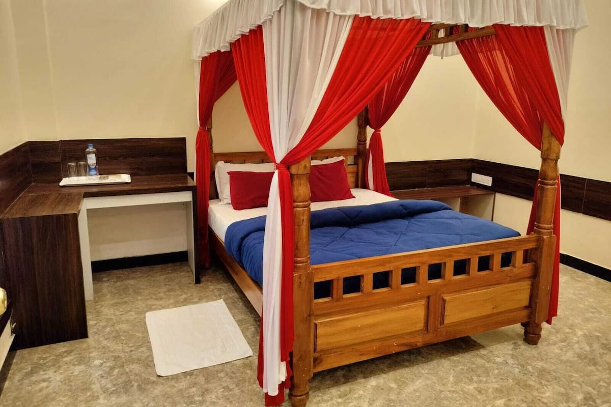 Un lit à baldaquin avec des rideaux rouges et blancs, une tête de lit en bois et une couvre-lit bleue.