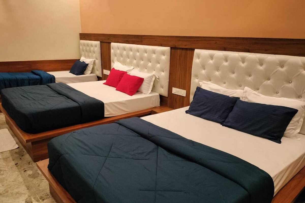 Une chambre d’hôtel avec deux lits, chacun doté d’une tête de lit capitonnée, de draps blancs et d’oreillers bleus et rouges.