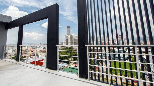 Un balcone con vista sulla città, tra edifici e un'area verde del parco.