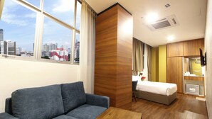 Camera d'albergo con divano, un letto, una parete decorativa in legno, televisione e vista sulla città.