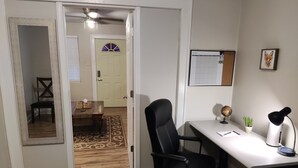A room with a desk, chair, and a mirror. There is a door leading to another room with a chair and a small table. - 1-bedroom private home just 4 minutes to Lucas Oil Stadium (Indianapolis)