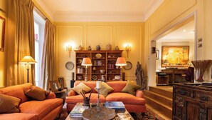Una sala de estar tradicional con un conjunto de sofás, una mesa de centro y una estantería llena de libros y objetos decorativos.