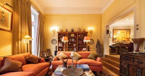 A traditional living room with a sofa set, a coffee table, and a bookshelf filled with books and decorative items.