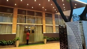 A modern hotel with a flat roof, large windows, and a well-lit entrance. - TGN SUITS - HOTEL (Raipur)