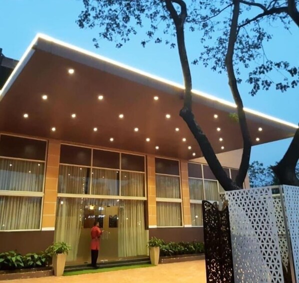 A modern hotel with a flat roof, large windows, and a well-lit entrance.