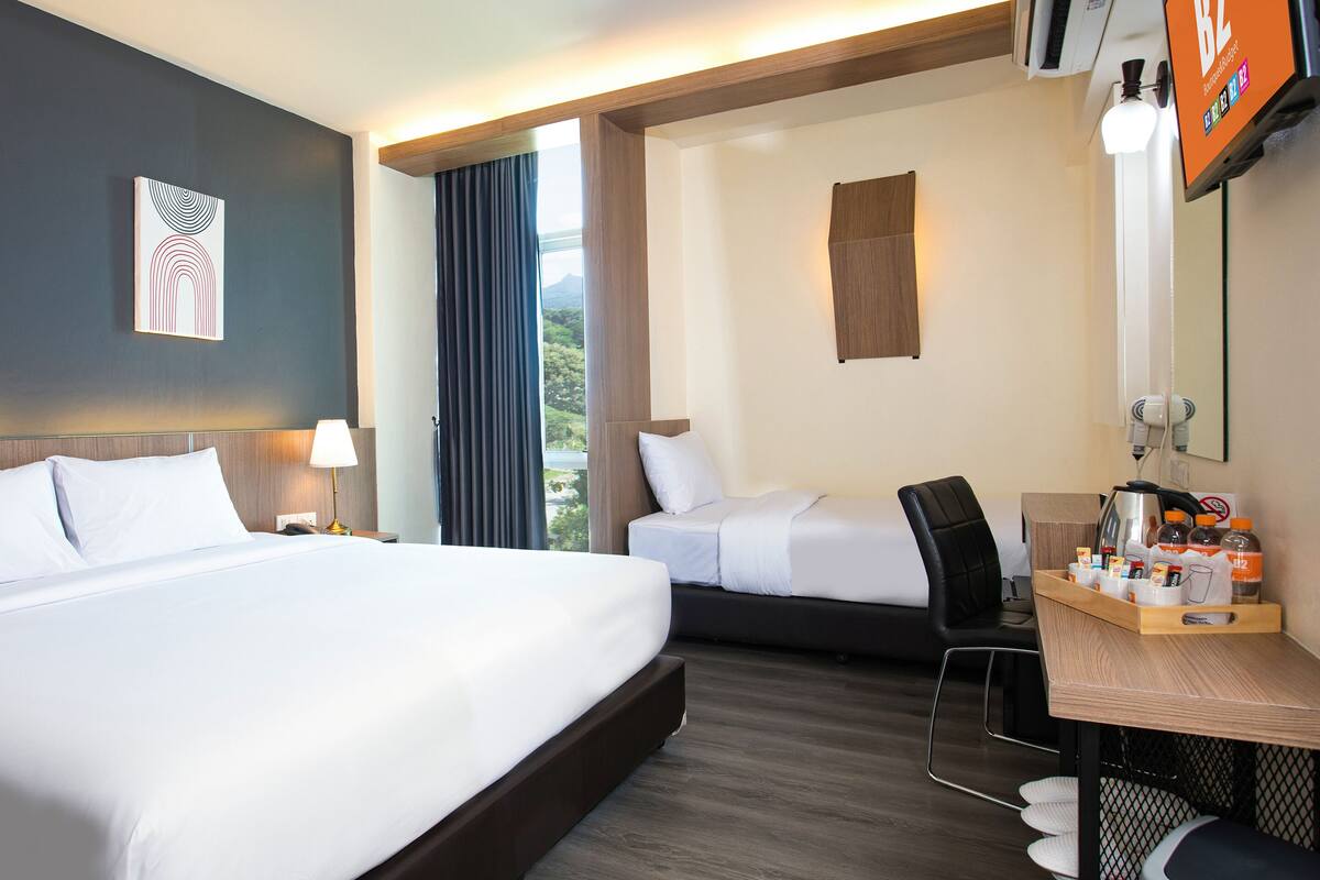 Ein Hotelzimmer mit zwei Betten, einem Schreibtisch mit Ausstattung und Blick ins Freie.