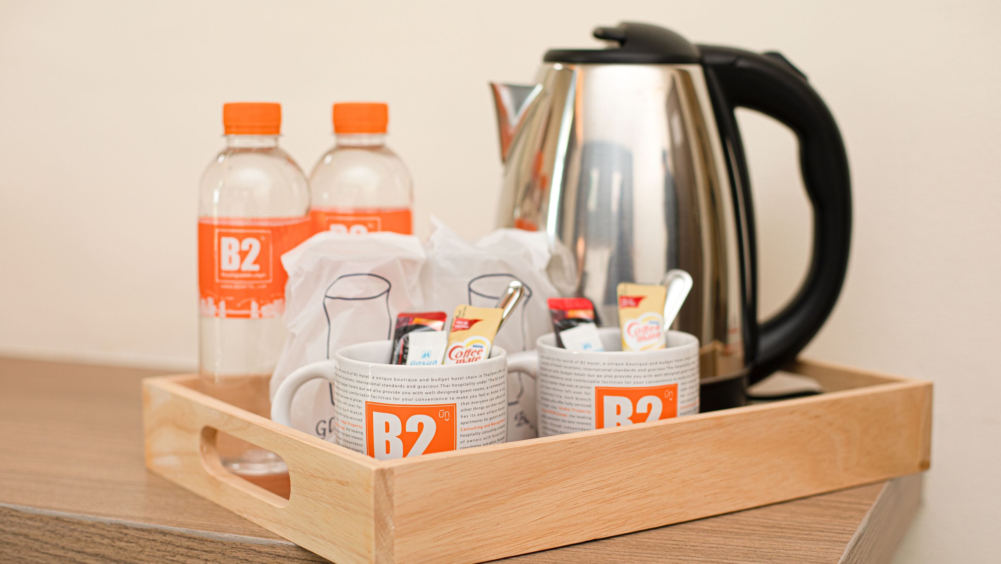 A tray with a coffee maker, two bottles of water, and two coffee mugs, each labeled with "B2".