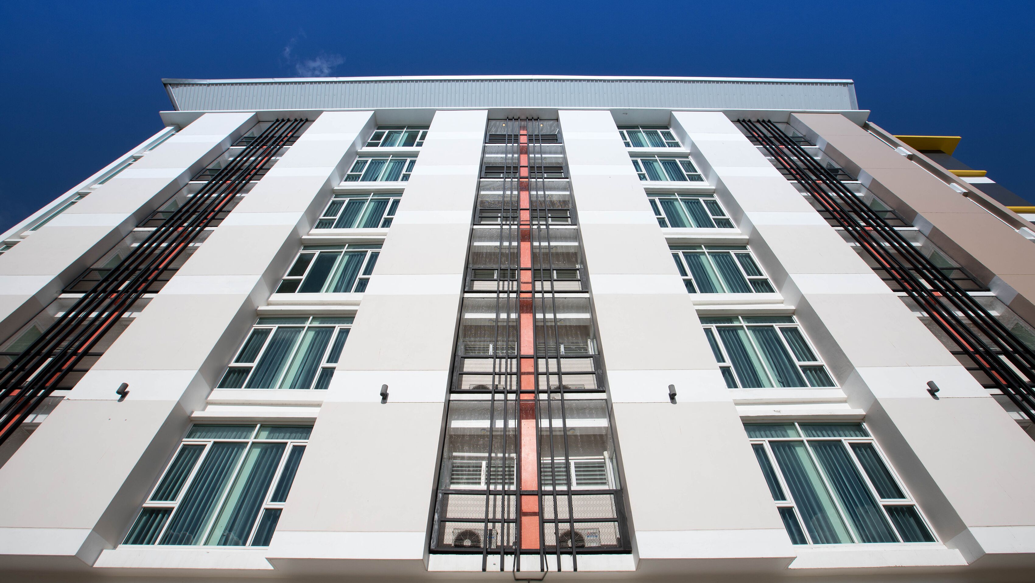 A multi-story building with a symmetrical facade, large windows, and a central vertical feature.