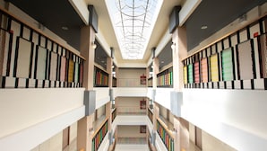 Un atrium à plusieurs niveaux, doté d’une verrière, de bibliothèques et d’un escalier.
