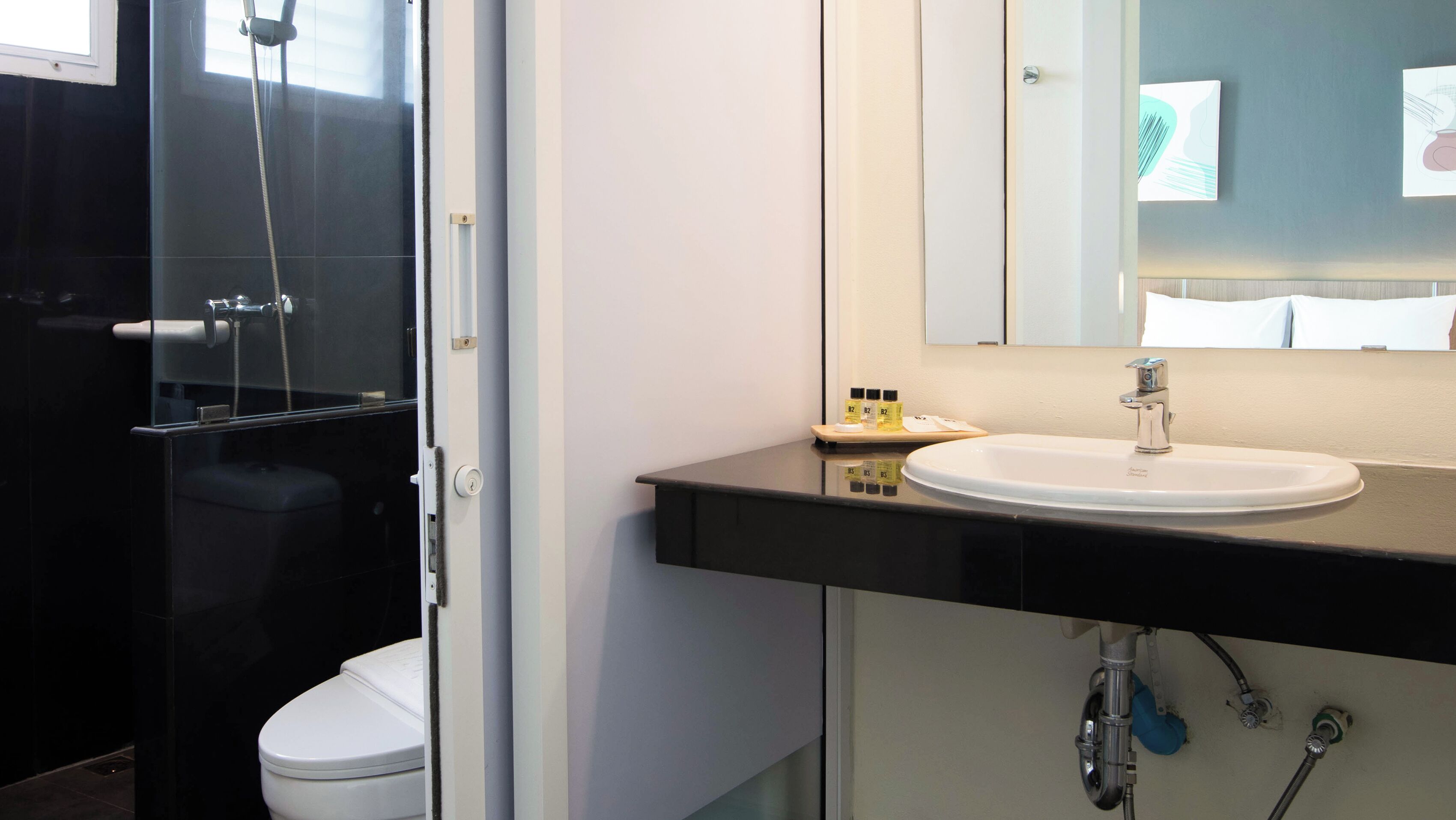 A modern bathroom with a glass shower enclosure, a white toilet, a sink with a mirror above it, and a towel rack.