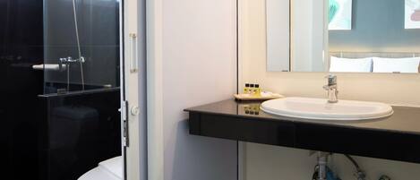 A modern bathroom with a glass shower enclosure, a white toilet, a sink with a mirror above it, and a towel rack.