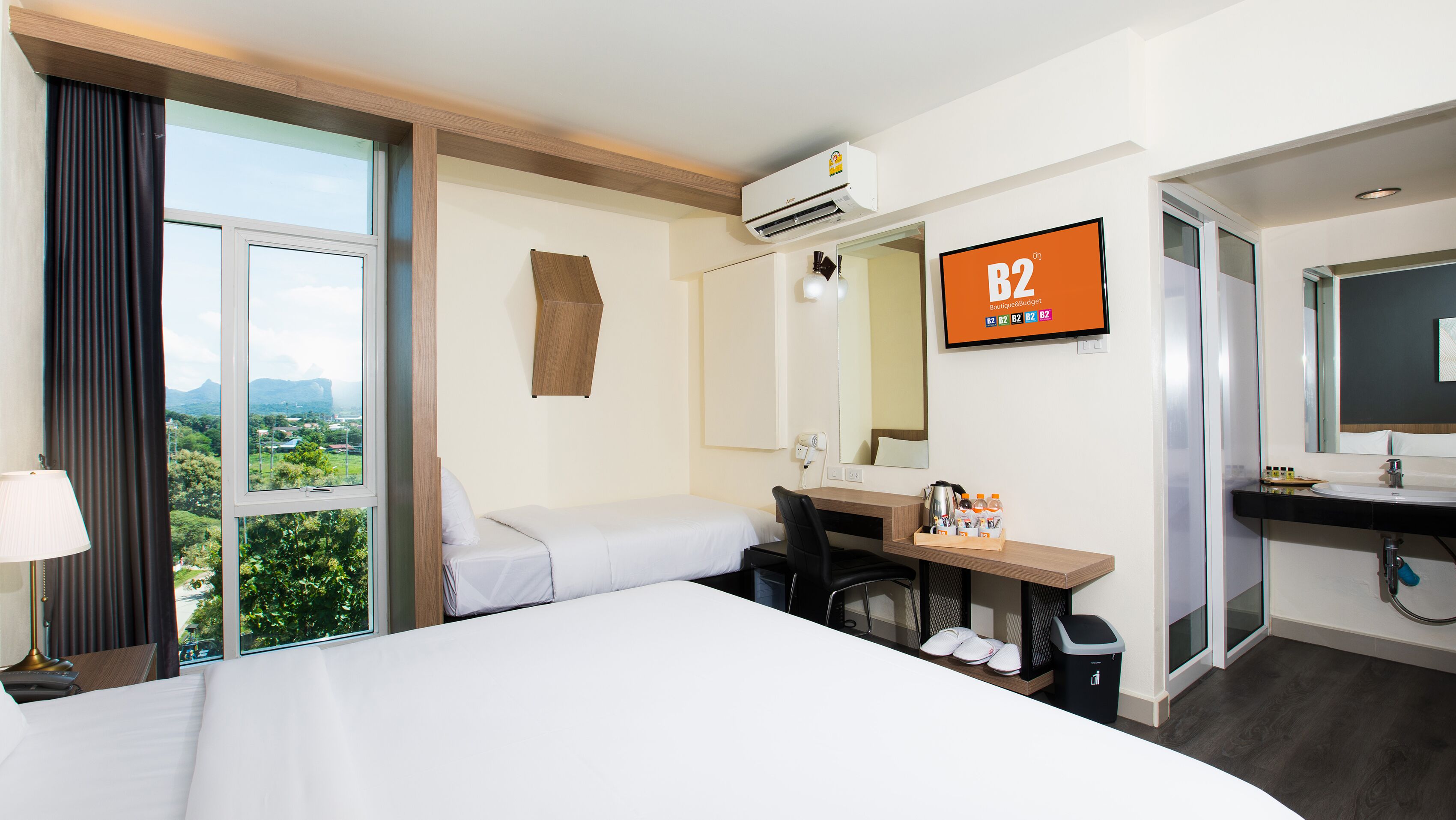A hotel room with a bed, desk, chair, and a TV displaying 'B2 Boutique & Budget'.