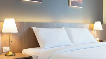 A hotel room with a bed, two bedside lamps, a nightstand, and a wall-mounted light fixture.