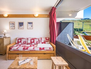 A cozy room with a wooden sofa, a small table, and a window with a view of a landscape.