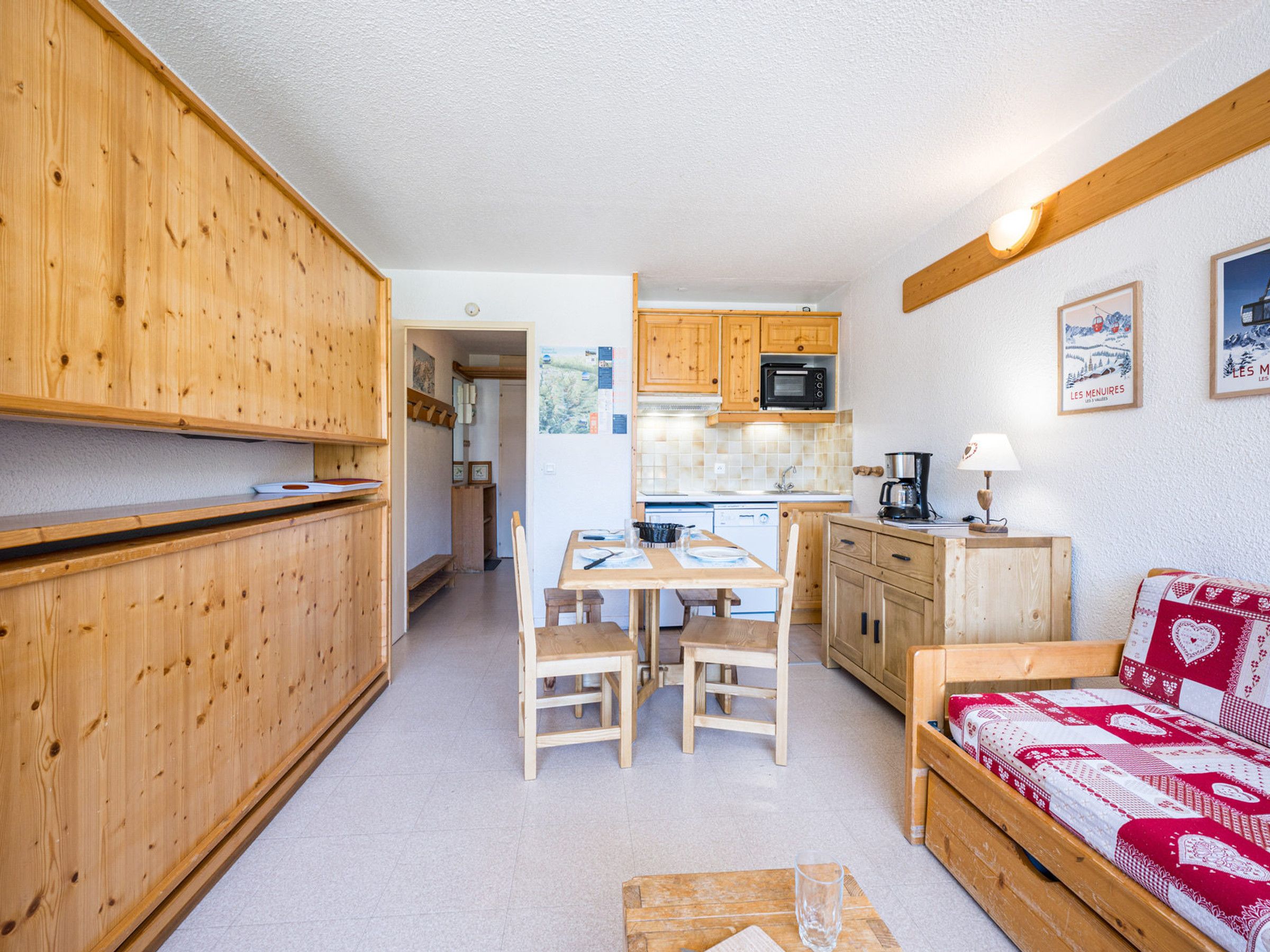 A compact kitchen with wooden cabinets, a dining table with chairs, a microwave, and a coffee maker.