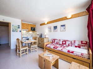 A compact living space with a kitchenette, a dining area, and a sofa with a patterned cover. - Bright studio with balcony, Ski-in/Ski-out, 4 pers (Les Menuires)