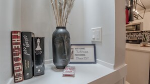 A shelf with books, a vase with dried plants, and a framed sign with a WiFi password. - Perfect Home Next To River Pathways & Downtown | 5+ Bedrooms and office (Calgary)