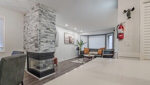 A modern living room with a fireplace, a sofa set, and a dining area. - Perfect Home Next To River Pathways & Downtown | 5+ Bedrooms and office (Calgary)