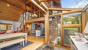 Un intérieur spacieux comprenant un coin repas, une cuisine et une grande porte vitrée donnant sur un jardin.