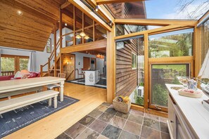 Un interior espacioso con comedor, cocina y un gran ventanal que da a un jardín.