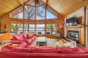 A spacious room with a large red leather sofa, a wooden coffee table, and a fireplace. - Sunset Chalet: Perfect Private Getaway! (Honeoye)