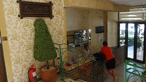 A reception area with a green plant, a fire extinguisher, and a counter with a television. - MAXWELL HOLIDAY CLUB (Marmaris)