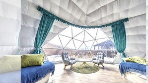 Ein geräumiger, moderner Innenraum mit geometrischem Deckenmuster, zwei Sofas mit Kissen und einem runden Couchtisch in der Mitte.