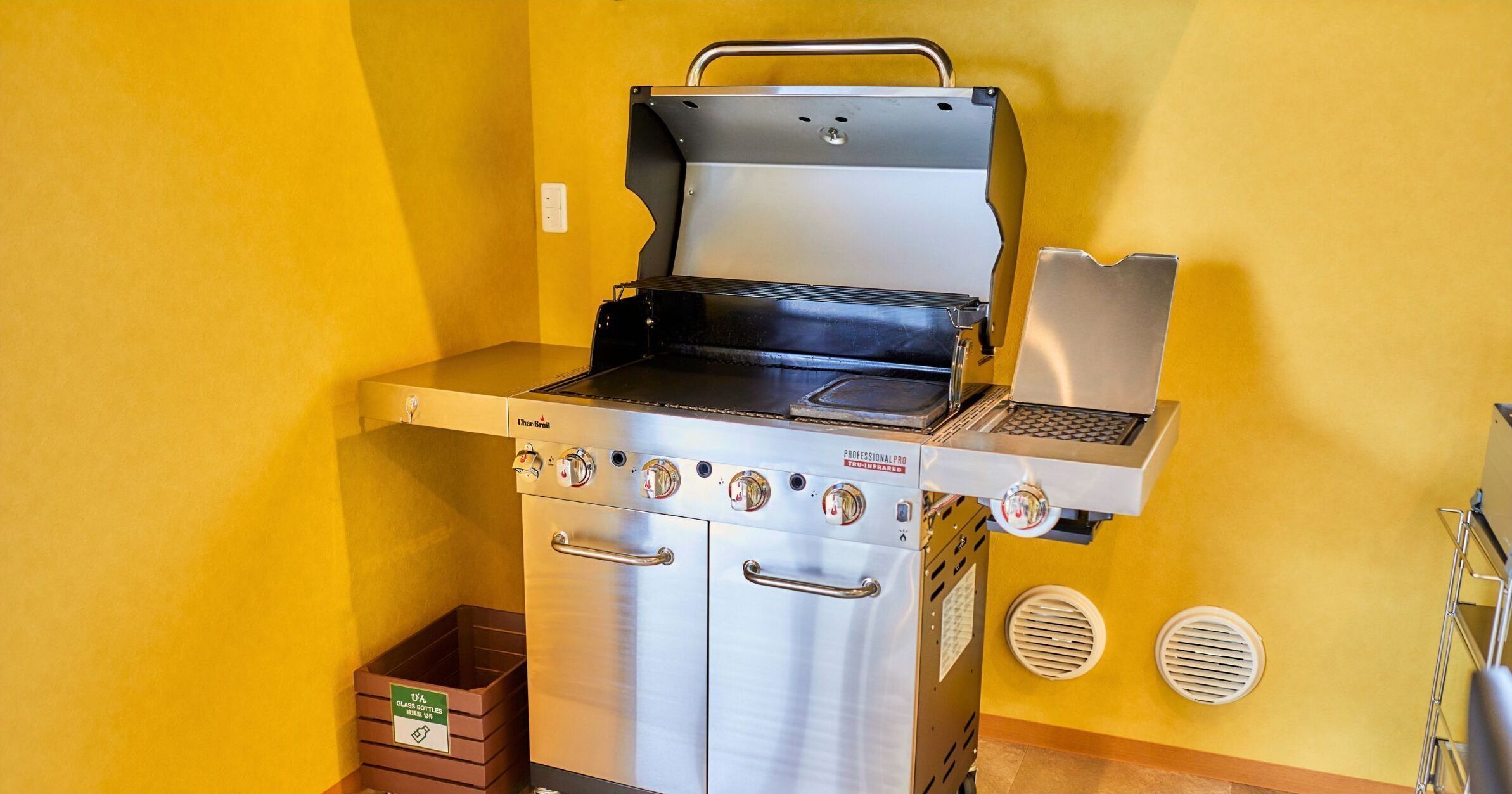 A commercial kitchen with a stainless steel range hood, a built-in grill, and a ventilation system.