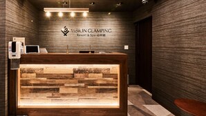Un comptoir d’accueil avec un panneau décoratif en bois, une enseigne au-dessus et un luminaire moderne.