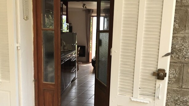 Een doorgang naar een kamer met een betegelde vloer en een plafondventilator.