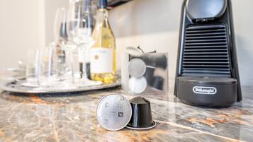 Un comptoir de cuisine avec une machine à café, une cafetière et un plateau contenant des verres à vin et des bouteilles.