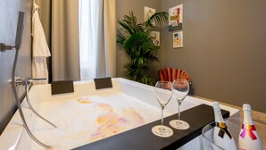 A modern bathroom with a bathtub, two wine glasses, and two bottles of champagne. - The Rif - Boutique Hotel (Pisa)