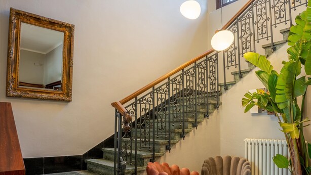 A staircase with wrought iron railings, a marble floor, and a large mirror on the wall. - The Rif - Boutique Hotel (Pisa)