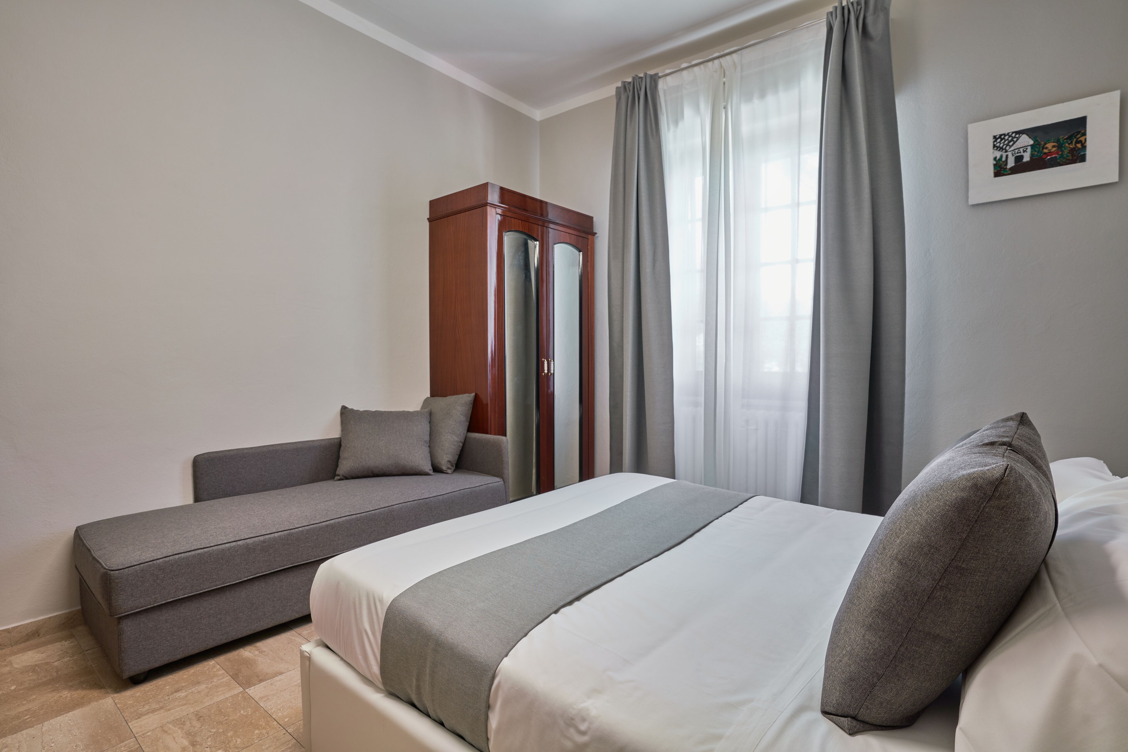 Una habitación de hotel con cama, sofá y armario.