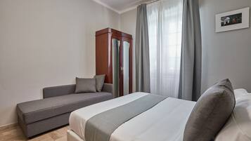 Una habitación de hotel con cama, sofá y armario.