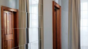 Un baño con un espejo grande, puerta de madera y piso de baldosas.