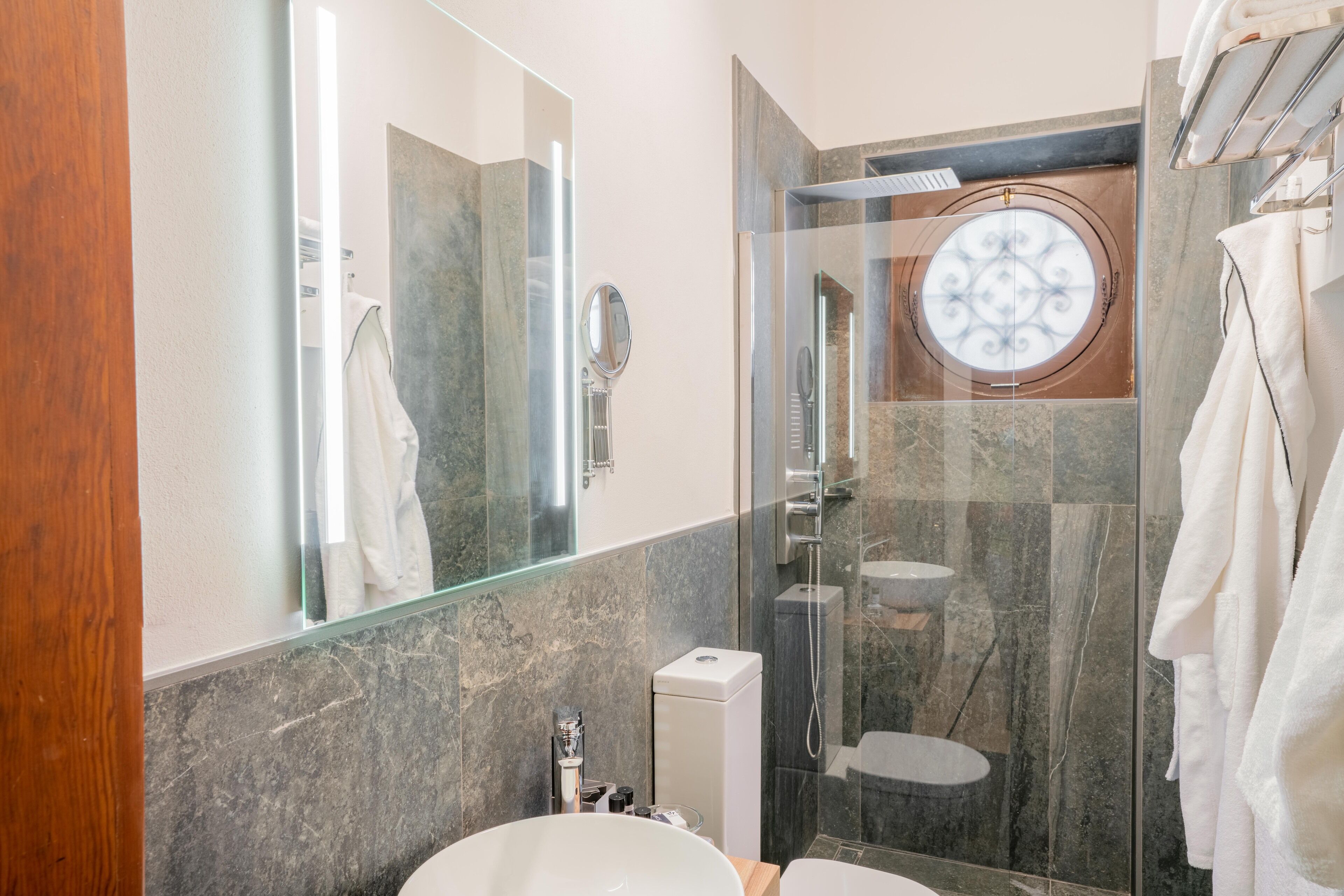 Un baño moderno con ducha de vidrio, un espejo grande y un lavabo blanco.